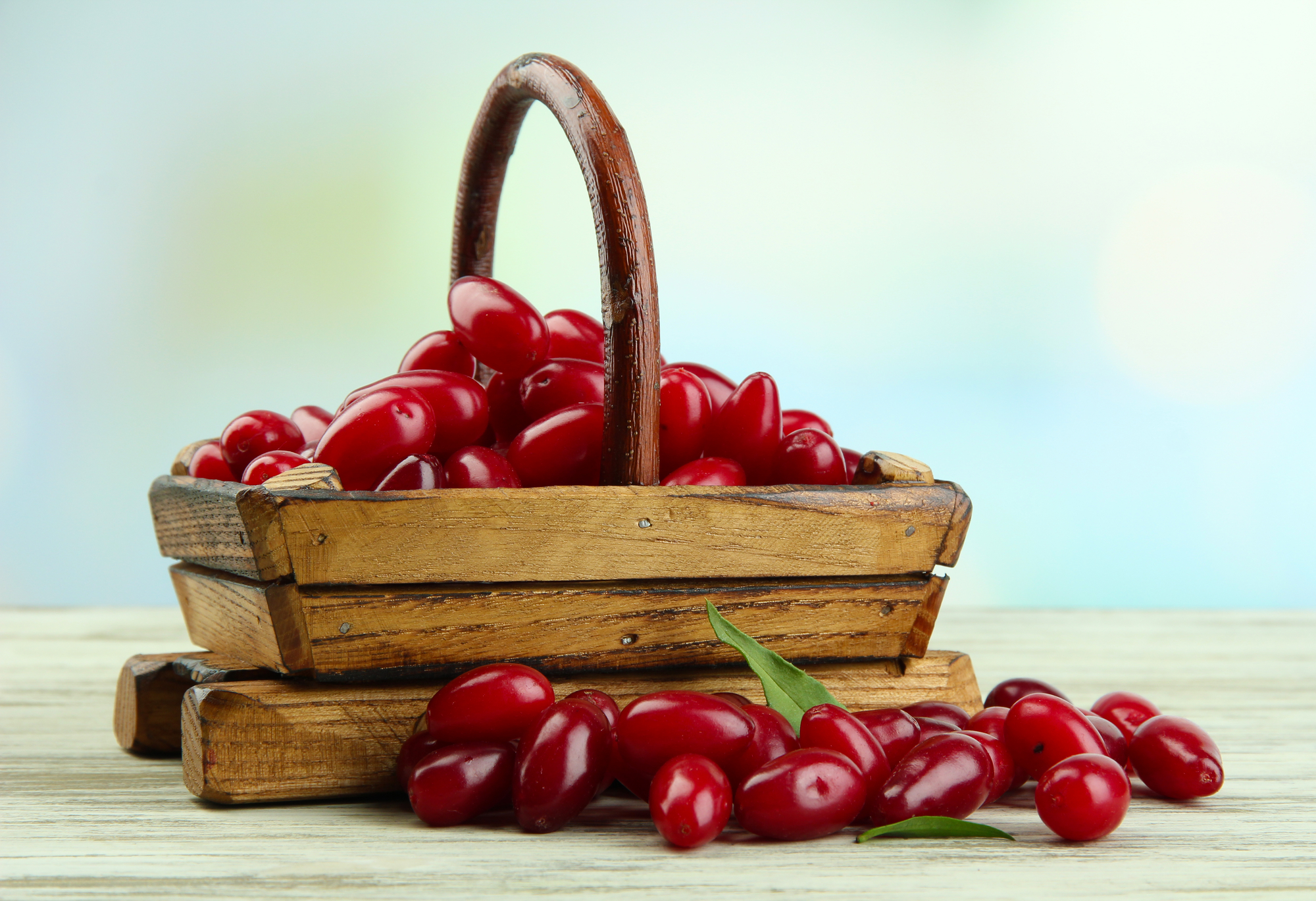 Fresh cornel berries in basket on wooden table